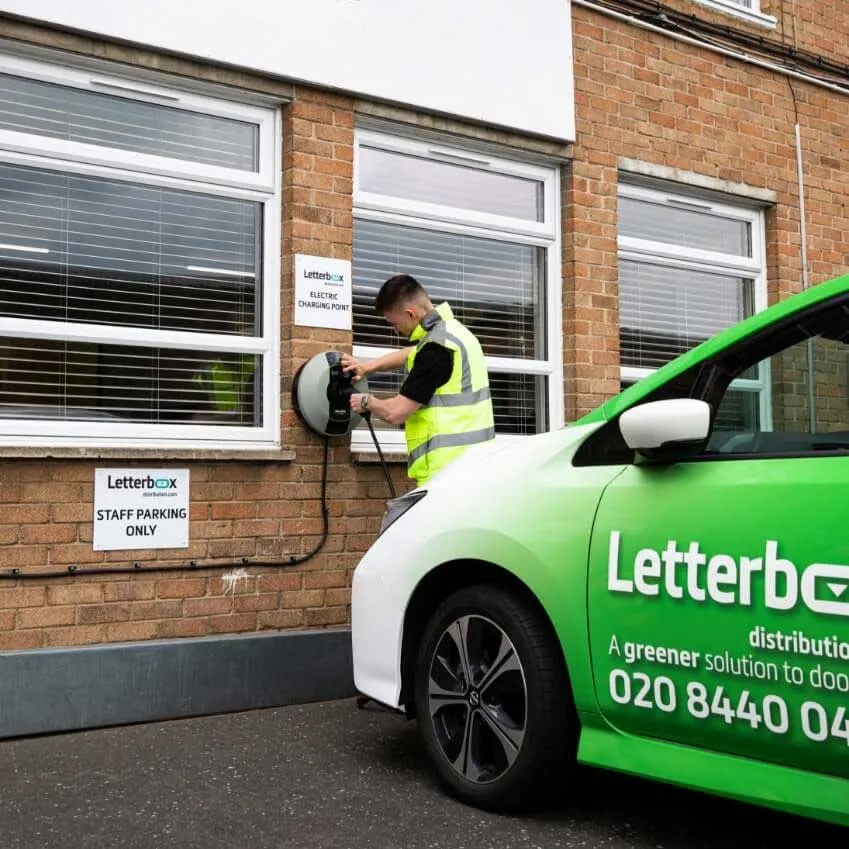 Letterbox operative charging a branded electric delivery car at the Letterbox staff electric charging point