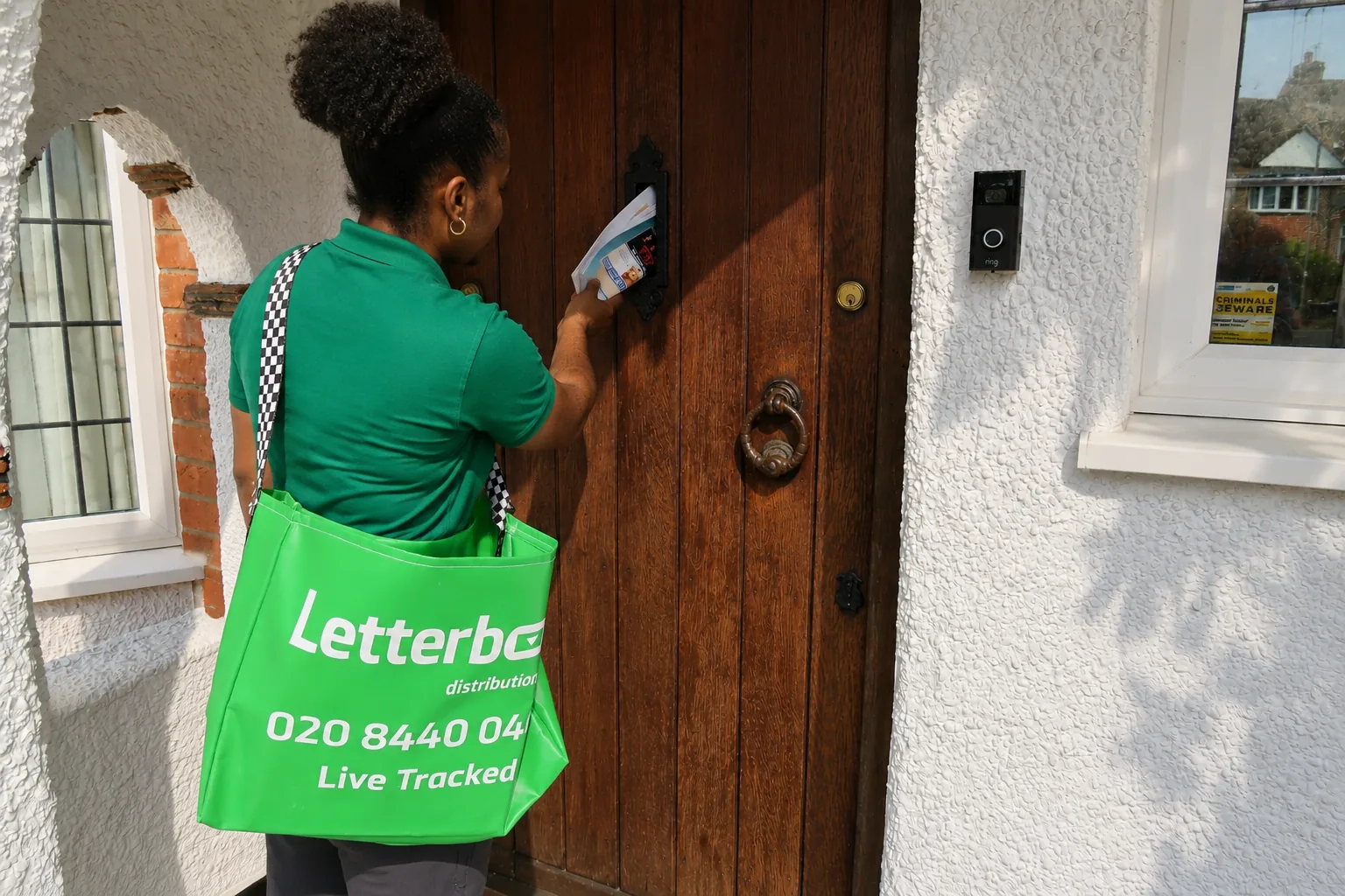 Letterbox operative unloading food waste caddies from an electric van