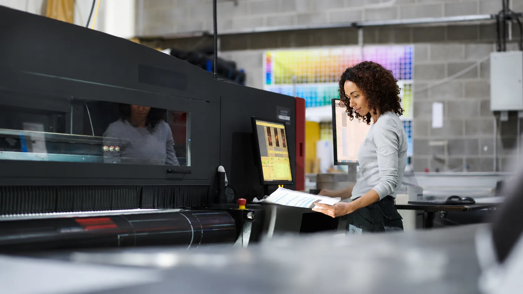 A print operator at a Letterbox production press, reviewing a colour proof on the production line.