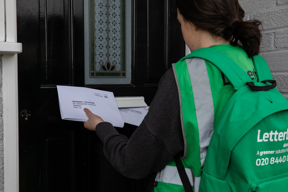 A woman delivers important letters through a door, using the letterbox